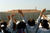 A photo of schoolgirls in the West Bank waving at Israelis who are on the other side of a wall