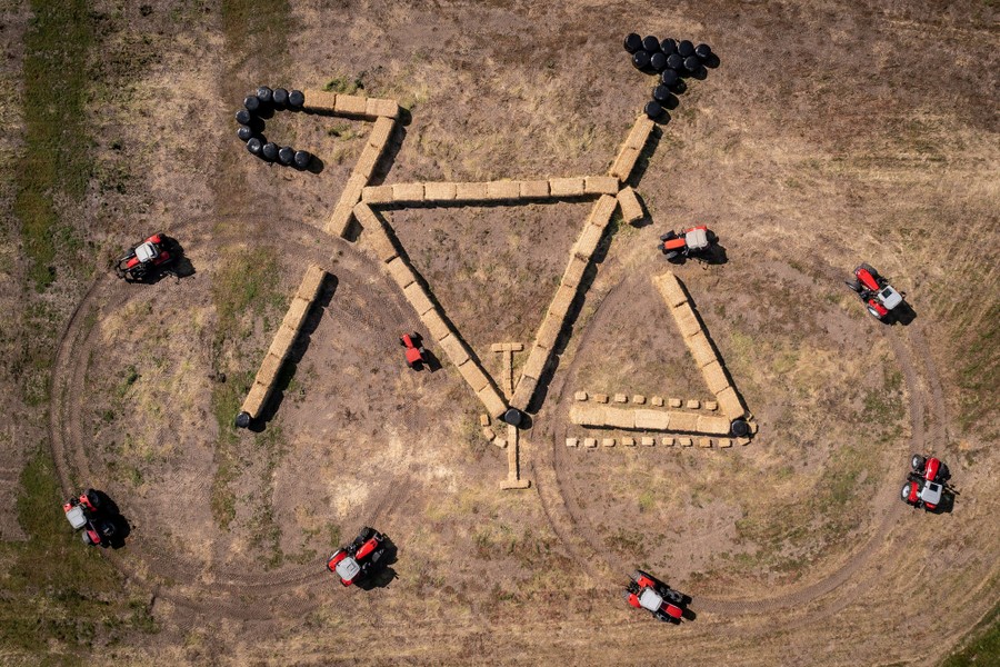 An aerial view of the outline of a bicycle, formed by hay bales and round tracks created by eight tractors