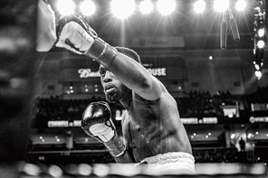 boxer making a left jab in the ring with bright lights and arena behind him