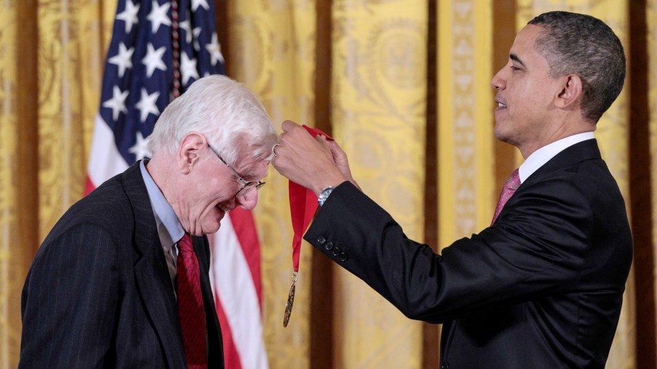 Barack Obama puts a medal around Gordon Wood in front of an American flag