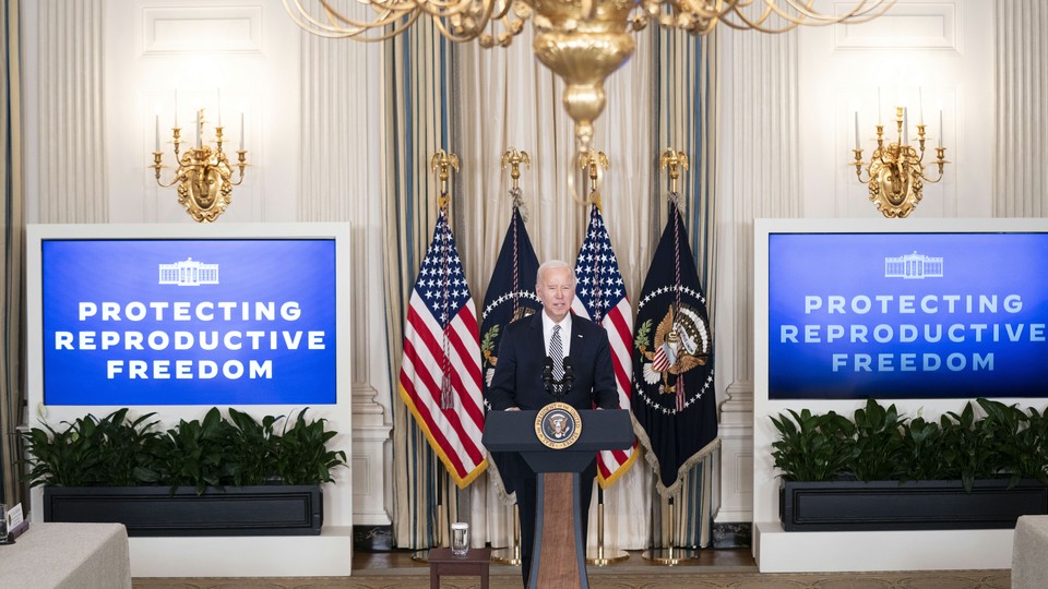 President Joe Biden in a room flanked by two screens that read: Protecting reproductive freedom