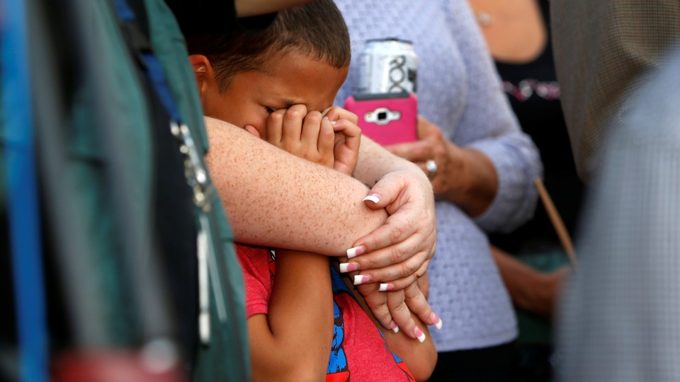 A young boy cries in a woman's embrace at a prayer vigil following the mass shooting in Las Vegas. 