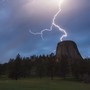 Lightning strikes near a tall, cylindrical rock formation.