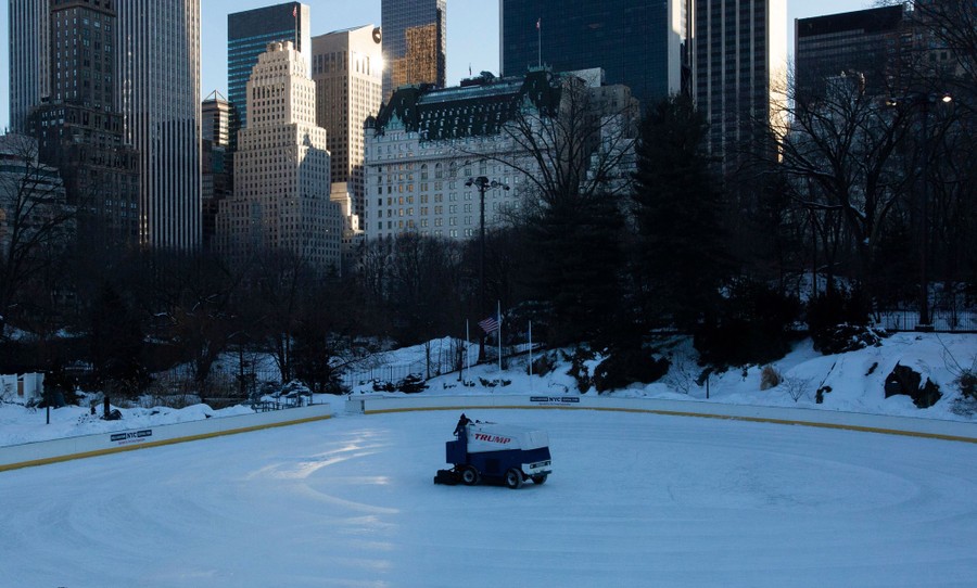An ice-resurfacing machine is driven across an empty outdoor ice rink in the middle of New York City.