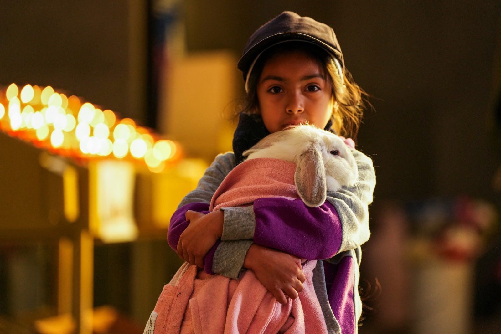 A girl carries a large rabbit, holding it during a pet-blessing ceremony.