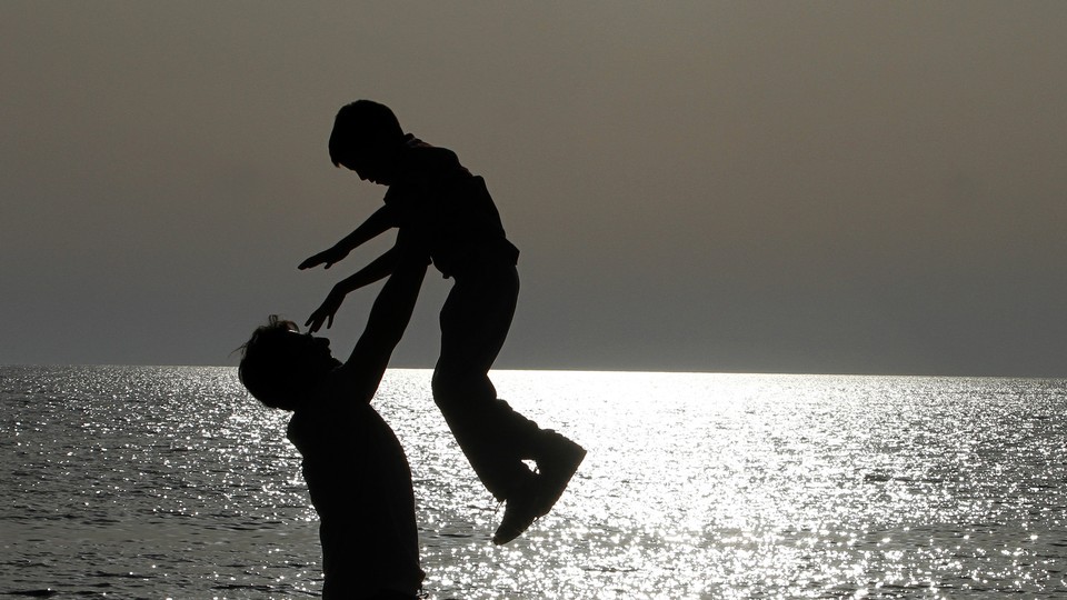 The silhouettes of a father and son playing on the beach