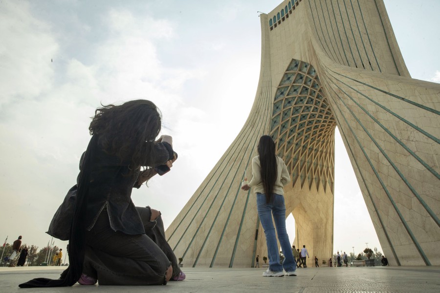 A girl takes a picture of another girl in Azadi Square in Tehran, Iran. Neither wears a hijab.