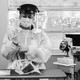 A black-and-white photo shows a nurse holding a swab taken from a patient for testing at the University of Iowa Hospitals and Clinics