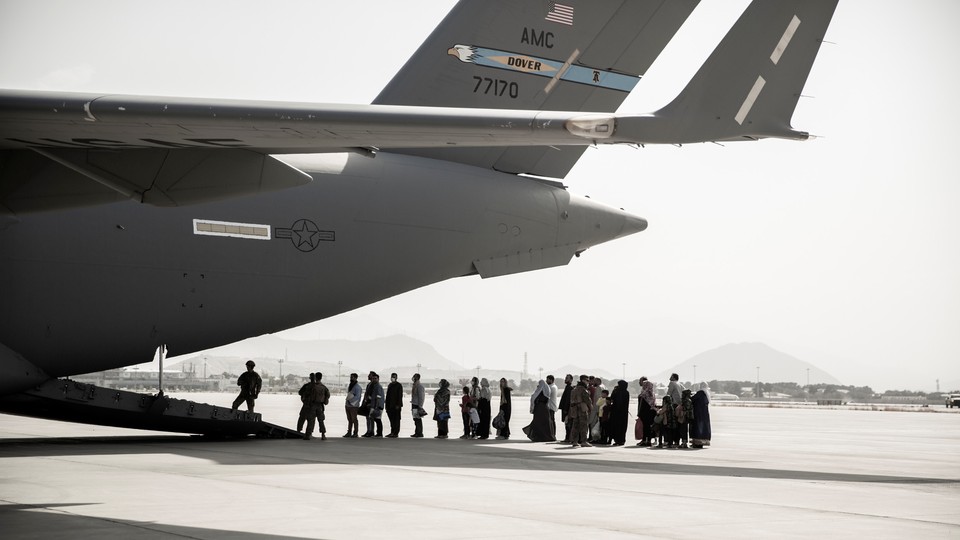 People wait to board a military plane.