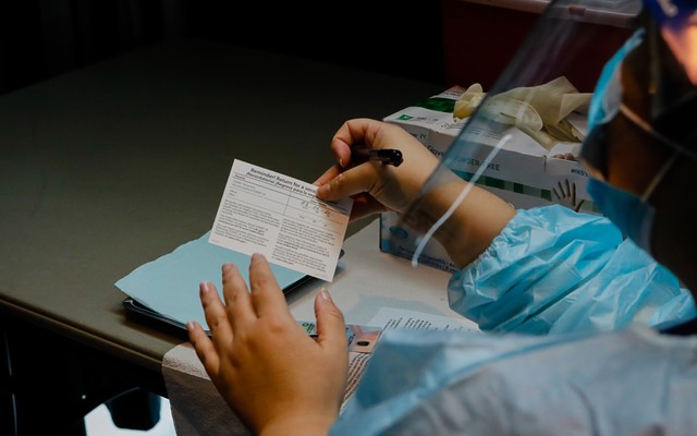 A doctor fills out a vaccination card