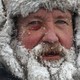 A close view of a bearded man wearing snow gear, his whiskers covered in ice