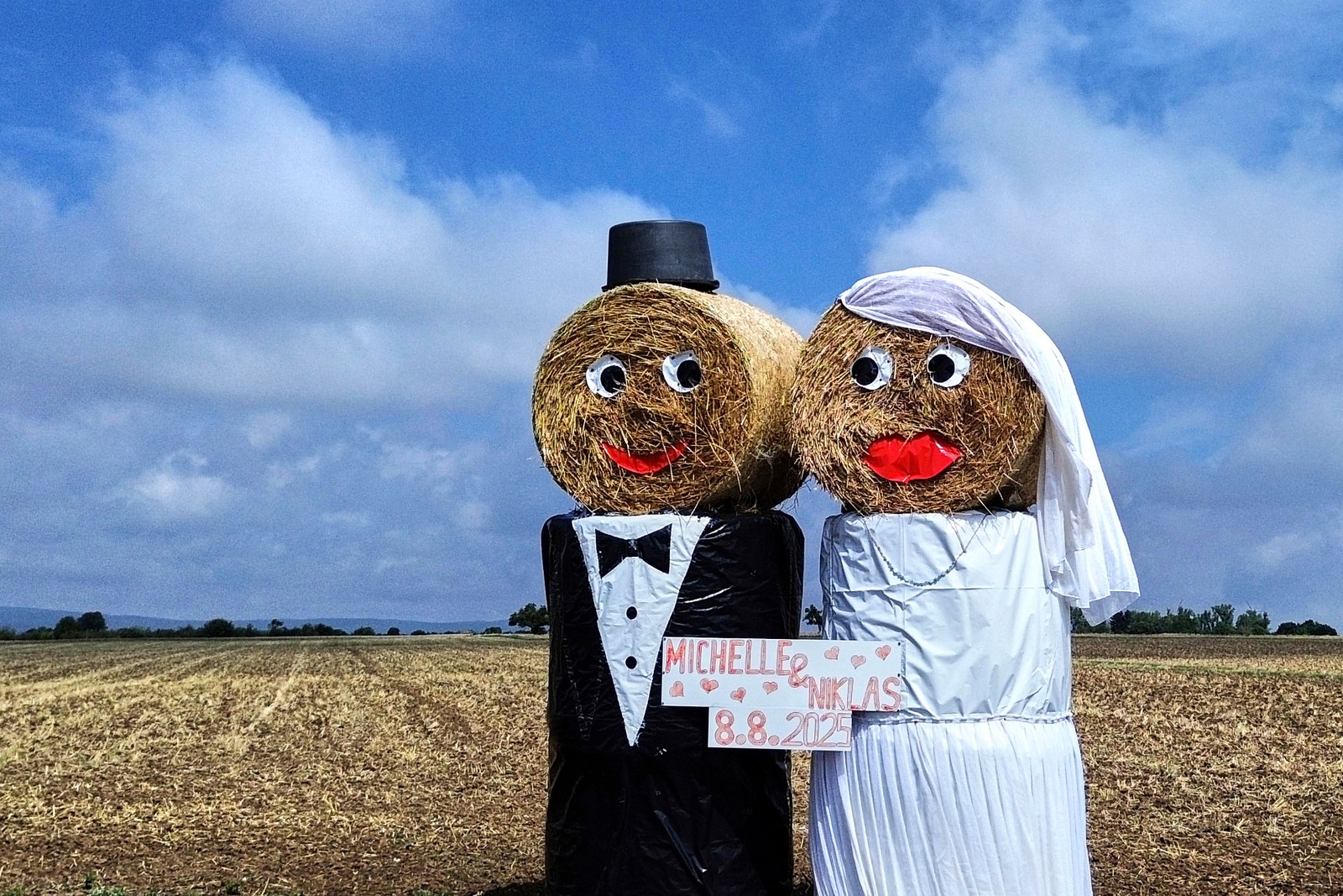 Straw bales are decorated as a wedding couple.