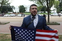 White-nationalist leader Jason Kessler poses with a flag across from the White House.