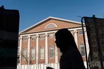 Photograph of someone in silhouette in front of a Harvard University building