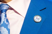 An up-close image of a suit, with a pin that reads "Chagos Islands Are British" on the blue lapel.
