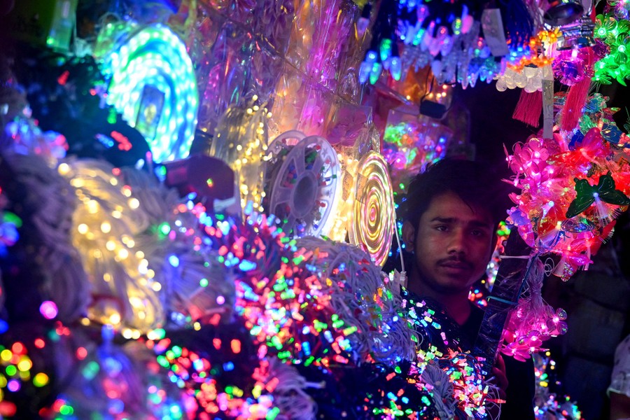 A shopkeeper's face is surrounded by decorations and lights.