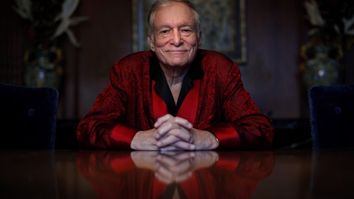 Hugh Hefner sits at a table.
