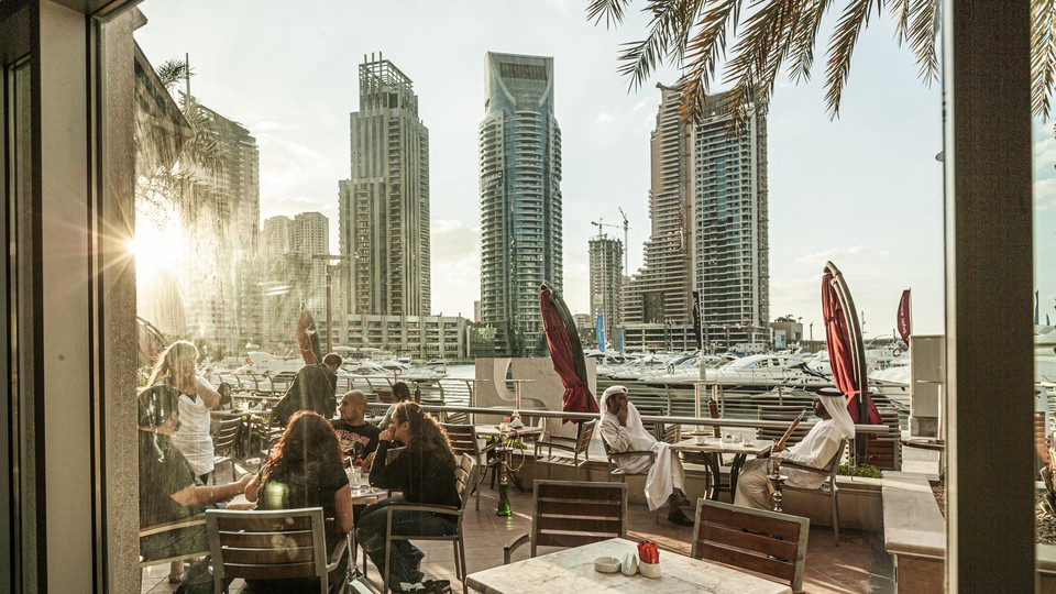Photograph of outdoor seating at a restaurant in Dubai with the sun shining on diners