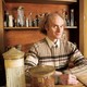 A portrait of the Czech scientist Jaroslav Flegr in front of a shelf of parasites in jars