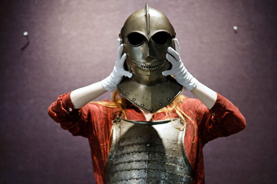 A person holds up an antique helmet.