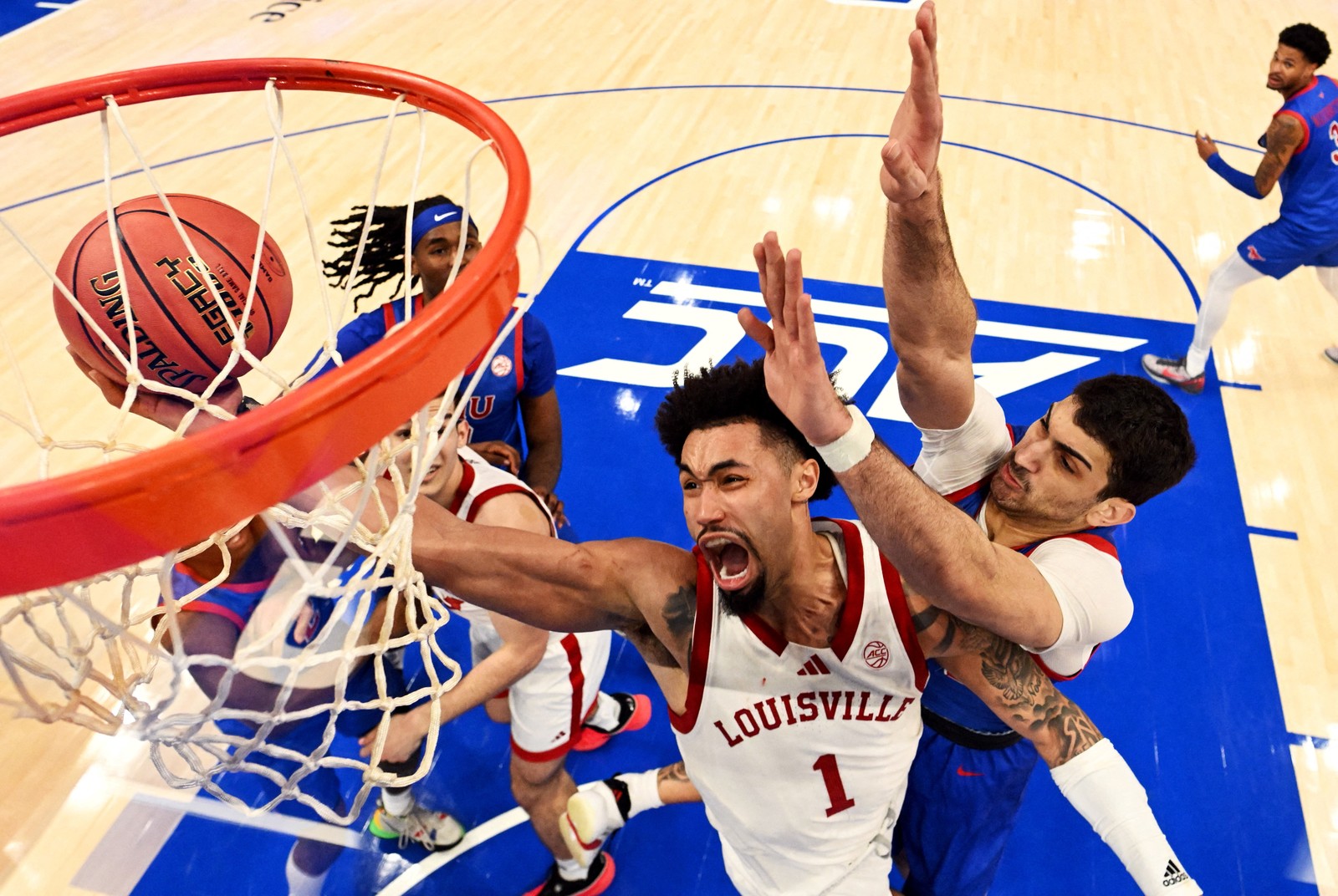 A basketball player tries to make a shot beneath the net, defended by several others.