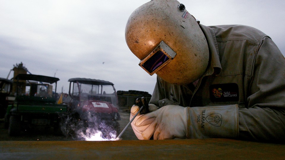 A welder works with a small torch and helmet on. 