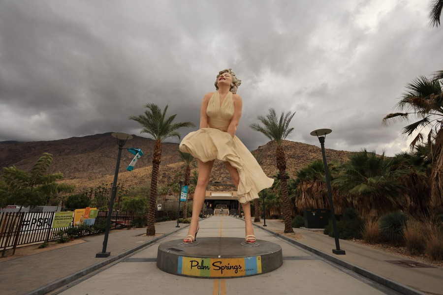 A statue of Marilyn Monroe stands outside beneath storm clouds.