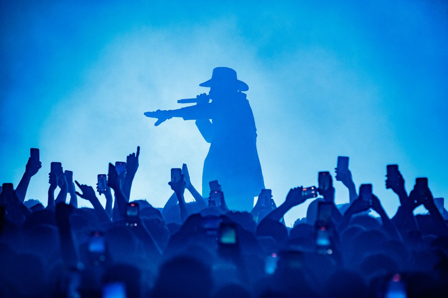 Audience members hold up hands and phones during a concert performance.