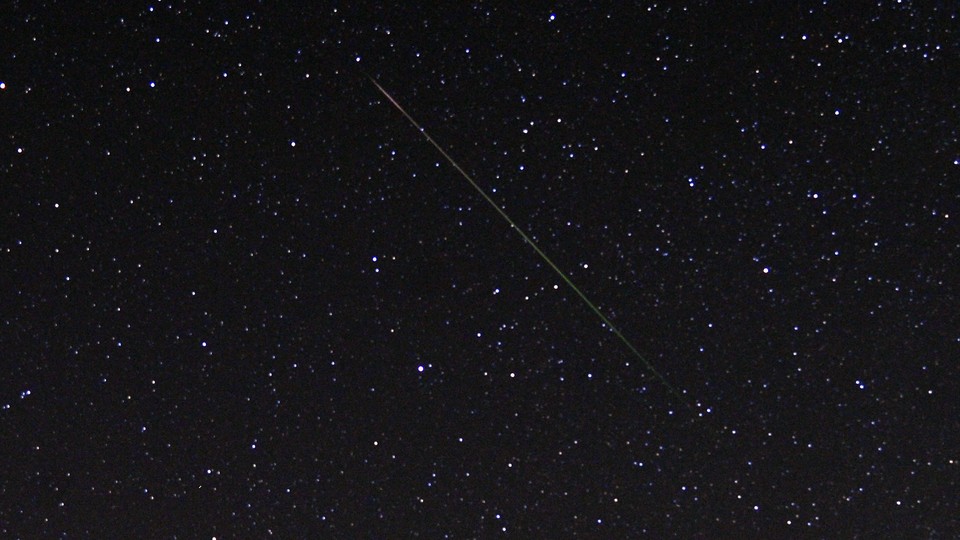 A thin diagonal line of light is shown against a starry sky.