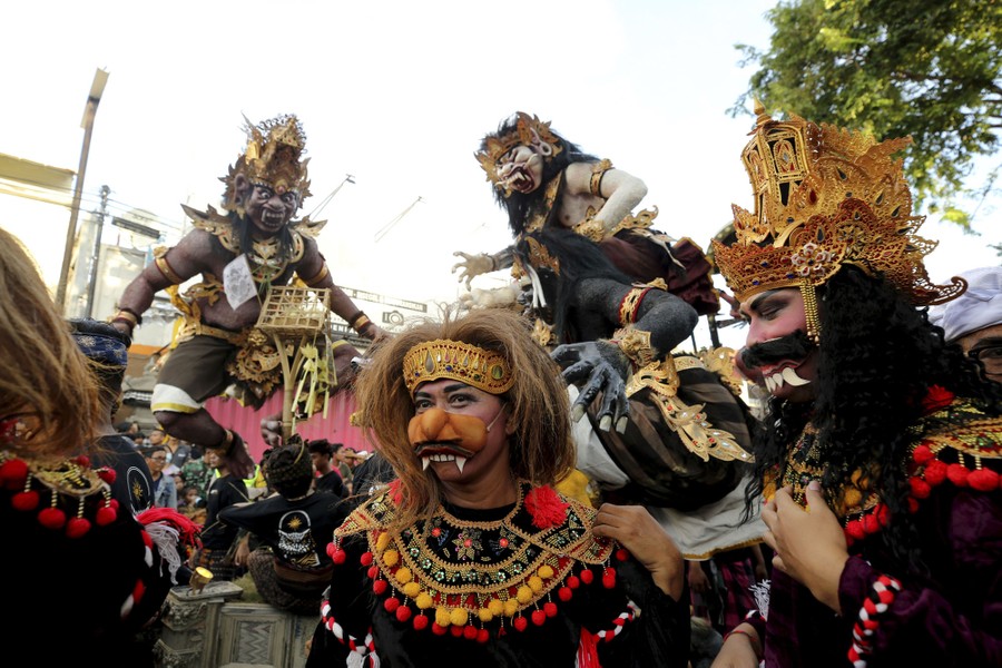 People wear costumes while carrying frightening sculptures in a parade.