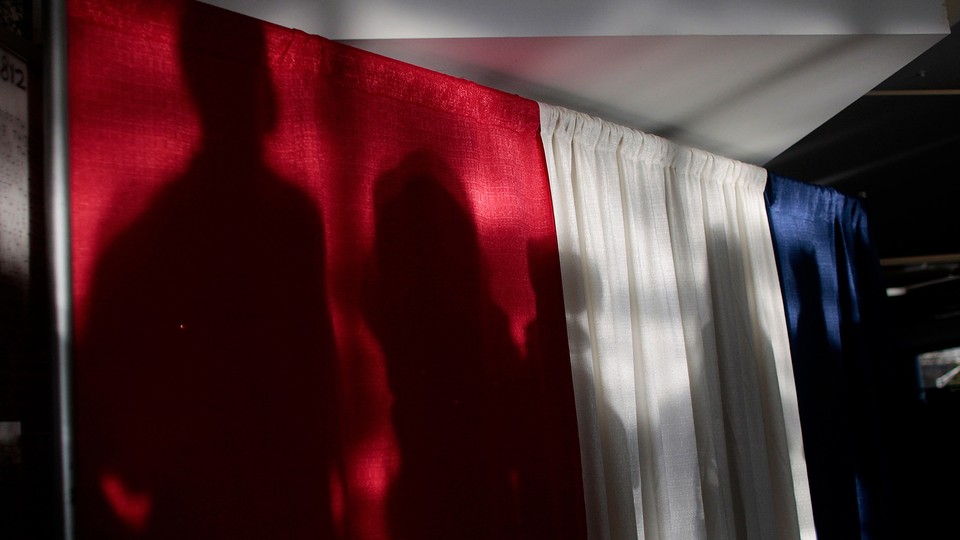 Shadowy figures appear on a large curtains that are the color of the American flag.