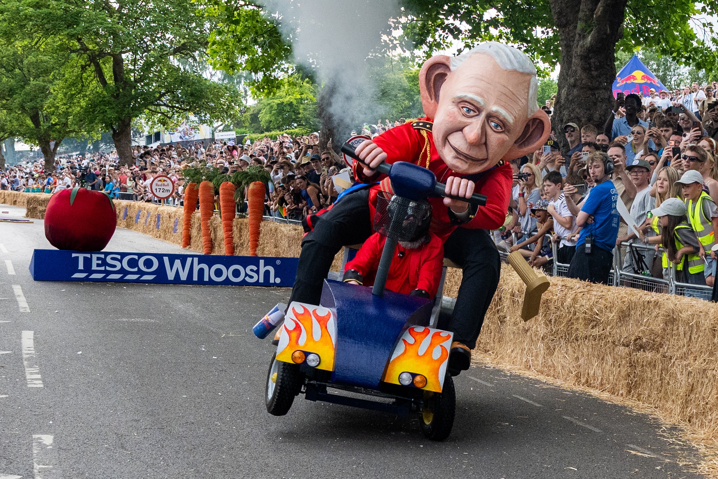 People race in a soapbox car depicting King Charles III on a mobility scooter