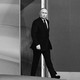 Black-and-white photo of Vladimir Putin in a black suit walking into a room
