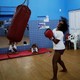 A girl stands next to a punching bag, looking like she is about to punch. 
