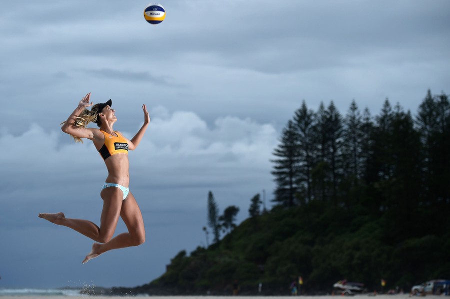 A volleyball player leaps to hit a ball in a posed photograph.