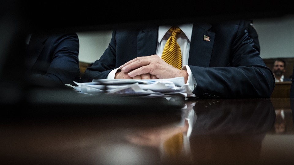 Donald Trump's hands rest on a stack of papers while he sits in court for his criminal trial
