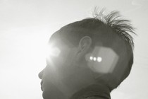 a young boy looking ahead, his face partially covered by the glare of the sun