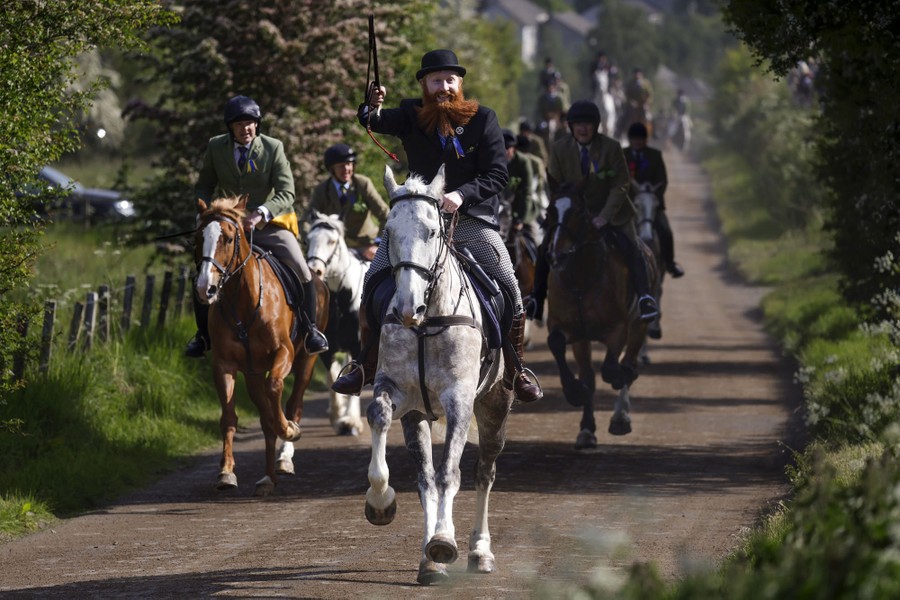 A group of riders on horseback run down a lane.