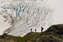 Hikers stand on a cliff overlooking Exit Glacier, in Alaska's Kenai Fjords National Park