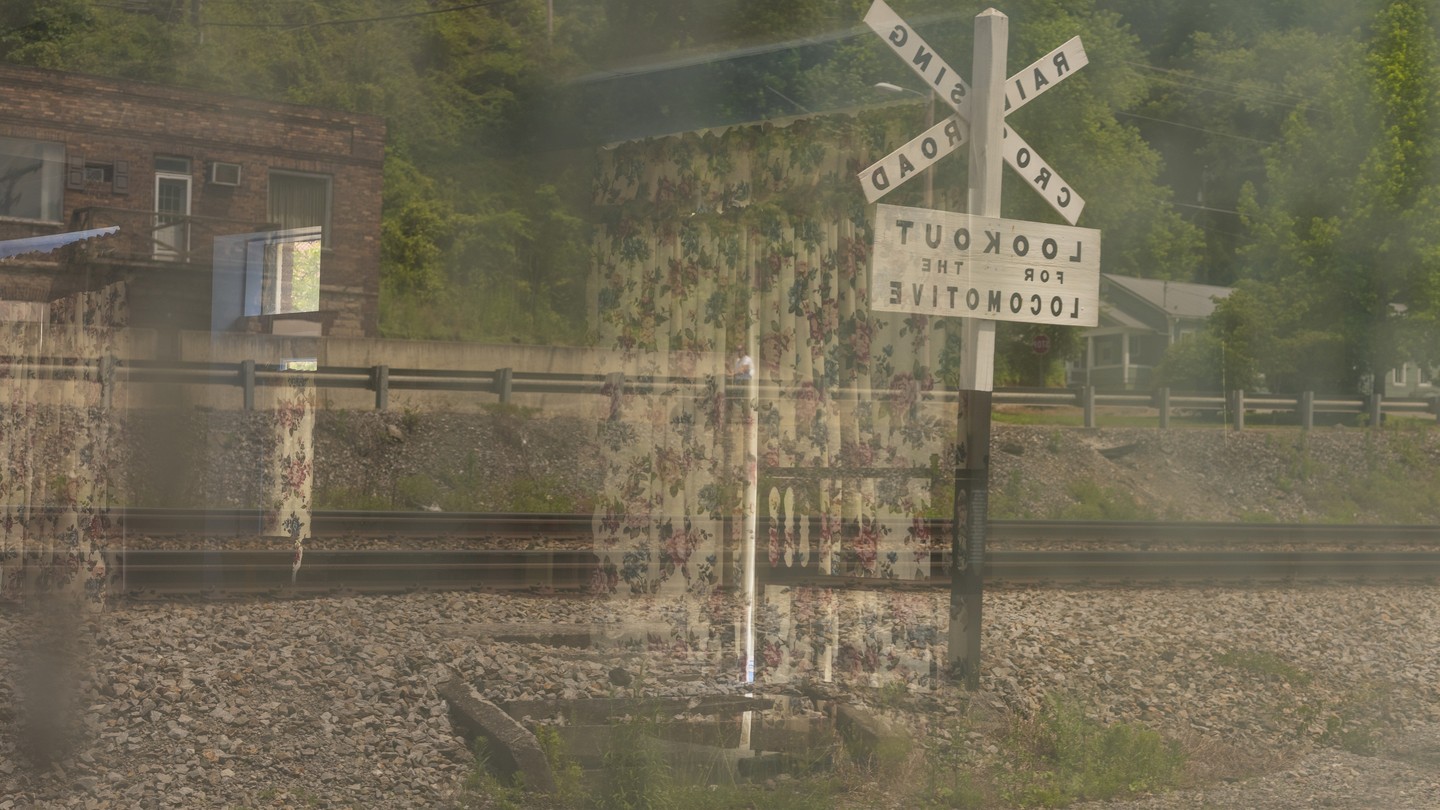 a double exposure of floral curtains on a railroad sign and building