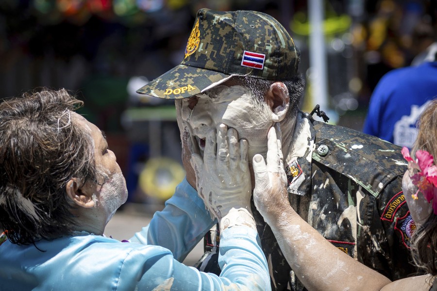 People playfully smear powder on the face of a police officer.