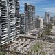 An aerial view of a long row of tall resort hotels along a beach, all heavily damaged by a storm