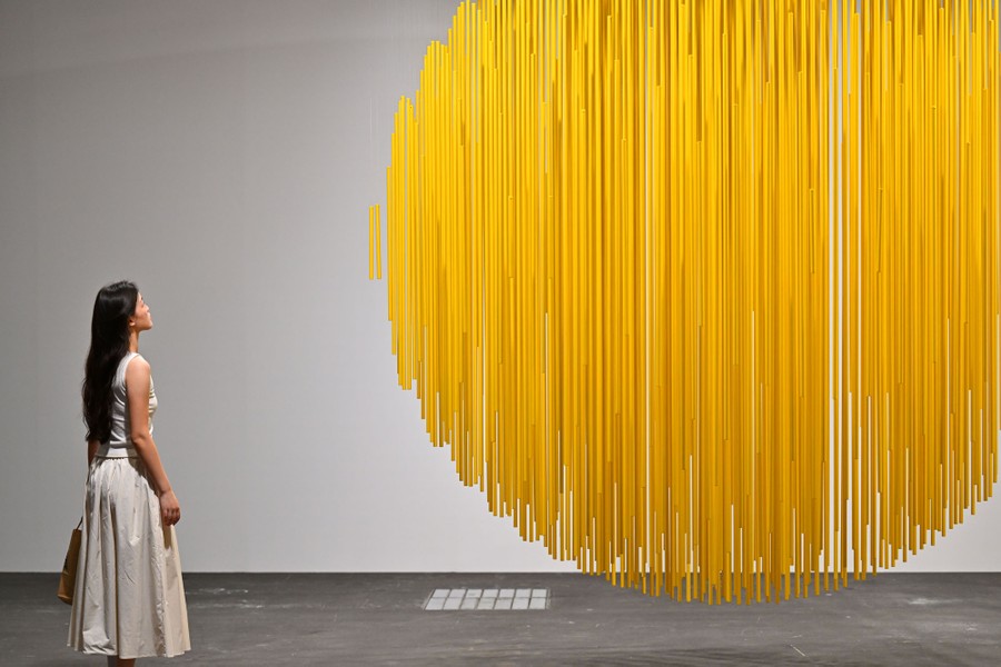 A person looks at a hanging, circular work of art.