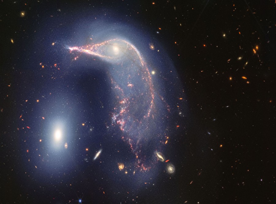 A telescopic view of two distant interacting galaxies, with one of them twisted into a shape that resembles the head and neck of a penguin