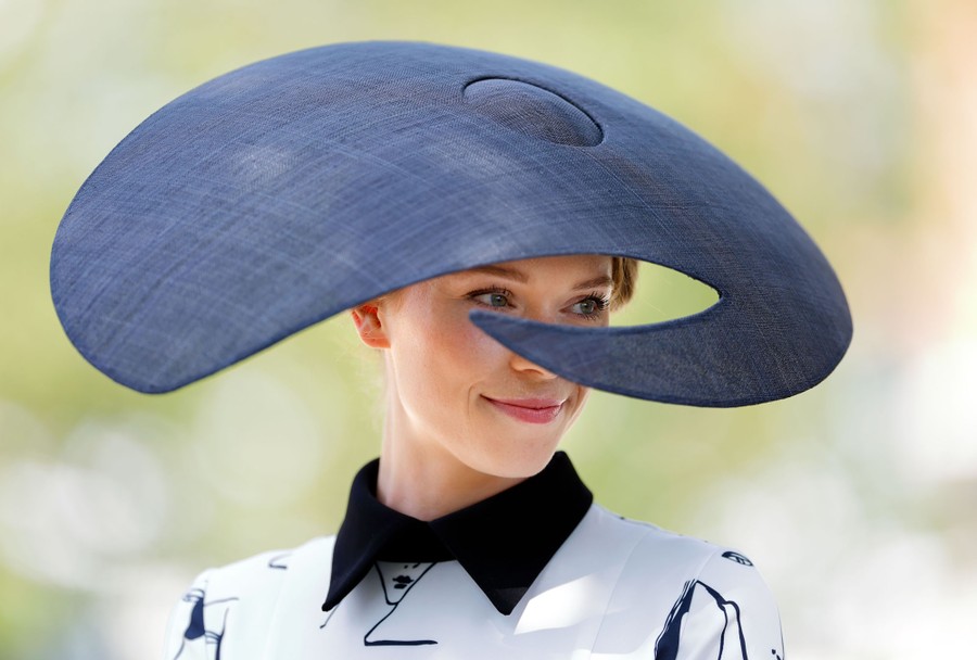 A person wears a large, swooping formal hat.