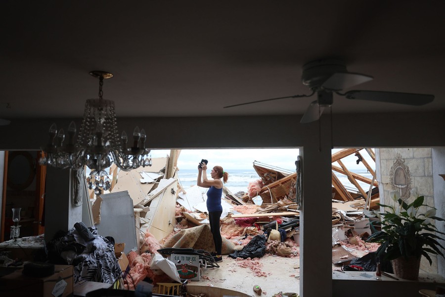 A person stands in the wreckage of a storm-damaged house.