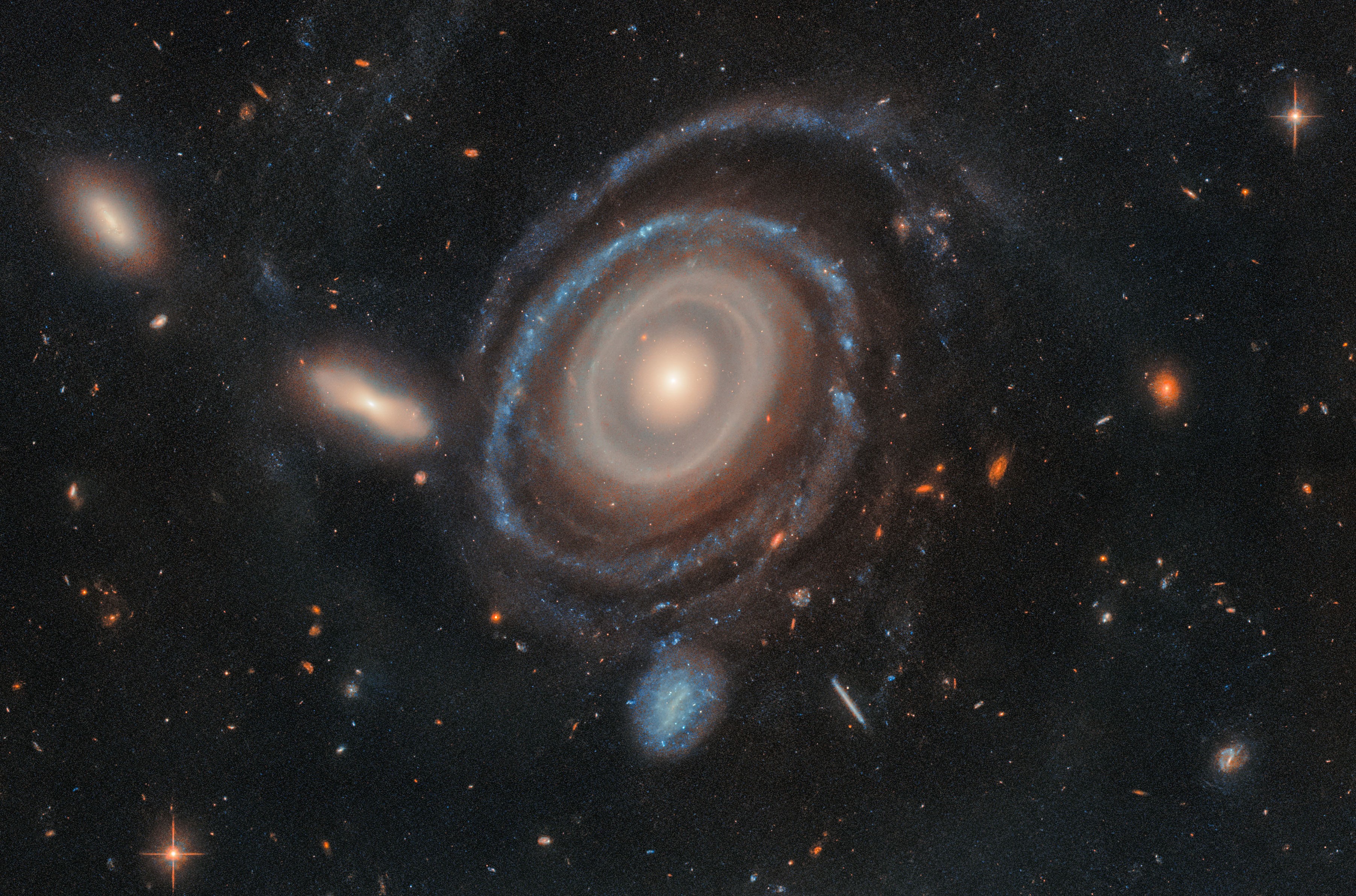 A spiral galaxy displaying by at least nine concentric rings around its core, backdropped by many other smaller, more-distant galaxies