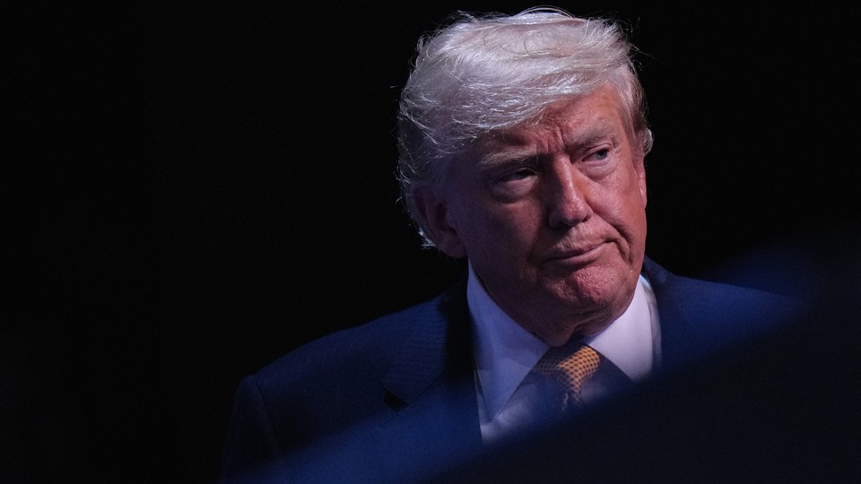 A photograph of Donald Trump’s face against a black background