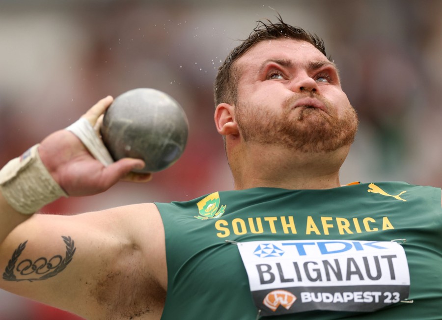 An athlete spins while preparing to throw a shot put, their face distorted by the spinning.