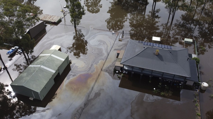 Oil slicks are visible in floodwaters that surround several buildings.